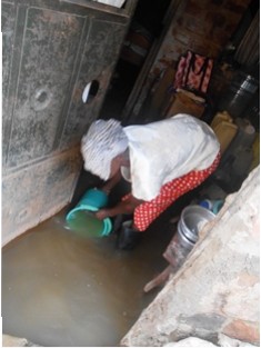 Janet bends down to scoop some of the dirty water that is mixed with sewage and waste from the nearby rubbish damp